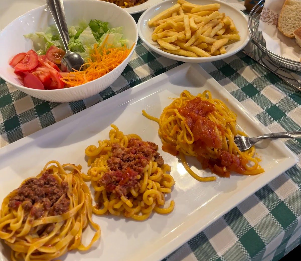 Piatto con tre tipi di pasta fresca: tagliatelle al ragù, gramigna e spaghetti al pomodoro, con insalata e patate
